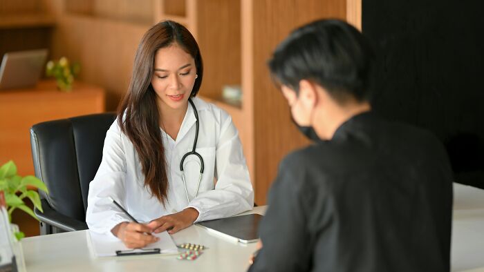 Female doctor in white coat with stethoscope talking to patient, representing benefits of working night shift overnight. - 6