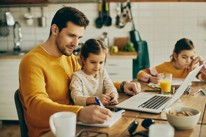 Man and children sharing reasons not divorced while working and studying together at home kitchen table.