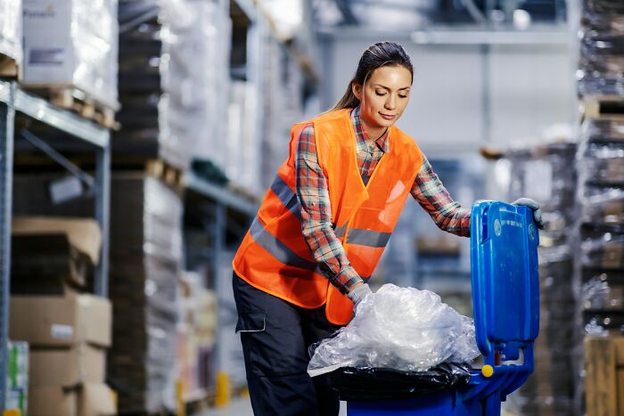 Woman in a warehouse wearing a safety vest recycling plastic, representing jobs to make 6 figures that don't get enough credit.