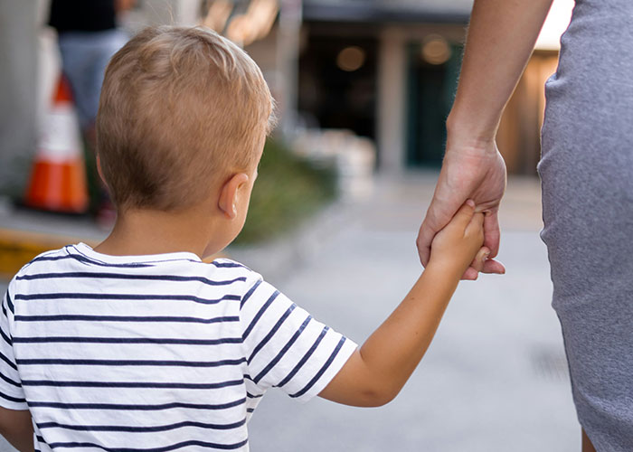 Young boy holding woman's hand walking outdoors, illustrating themes of ex-husband's new wife and feelings of zero regret. - 7