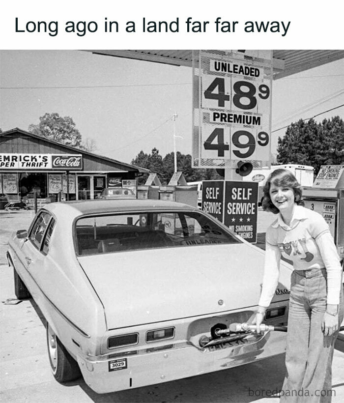 Woman in vintage '80s outfit pumping gas at a retro gas station with old-fashioned prices and signage.