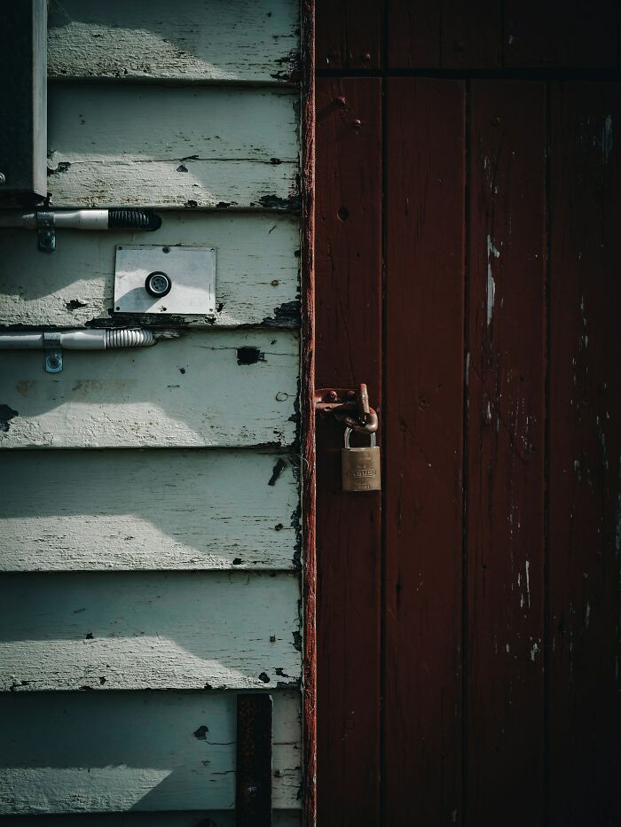 Old wooden door with a padlock next to weathered siding, symbolizing parents punishing their kids by locking them away.