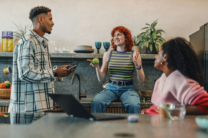 Three friends chatting happily in a kitchen, showcasing positive green flags in social interactions.