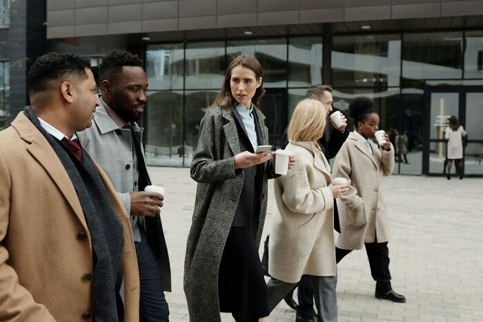 Group of diverse professionals walking outside an office building, showing green flags in relationships through conversation and connection