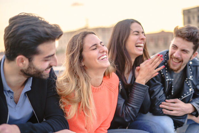 Four friends laughing together outdoors, sharing moments of joy and green flags in healthy relationships.