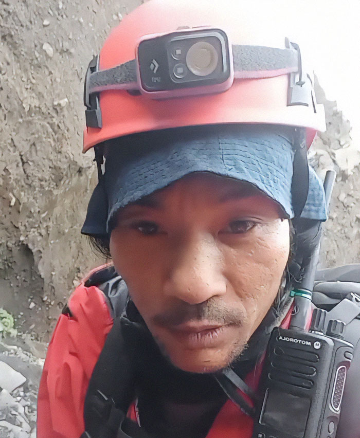 Hiking guide wearing helmet and radio equipment during active volcano expedition inside volcanic terrain