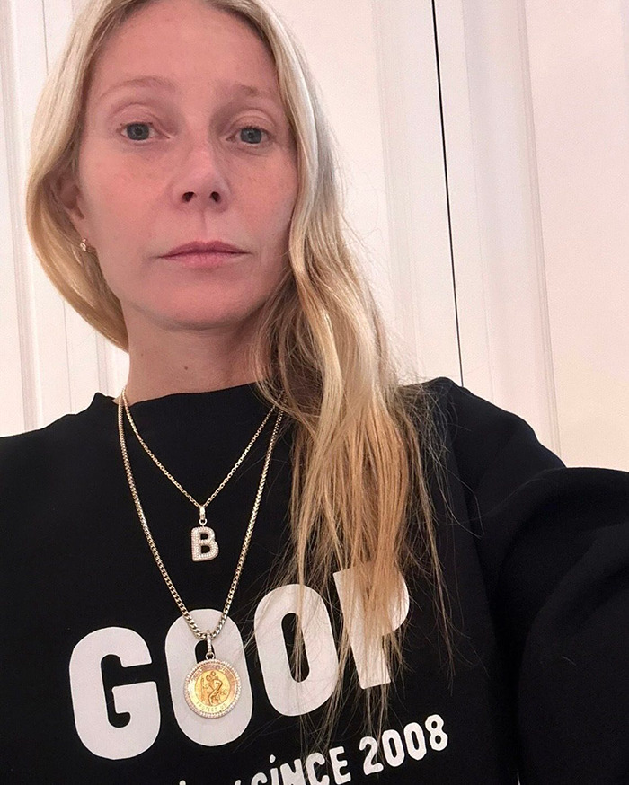 Gwyneth Paltrow wearing black GOOP sweatshirt and gold necklaces, showing casual style in a close-up selfie. - 5