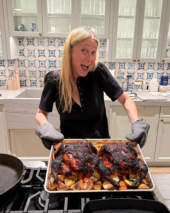 Gwyneth Paltrow holding a tray of burnt food in a kitchen, raising concerns about her trash-handling skills. - 8