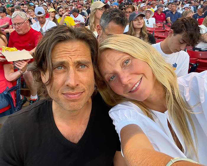 Gwyneth Paltrow smiling with a man at a crowded outdoor event, fans react to her trash-handling skills in cooking video. - 7