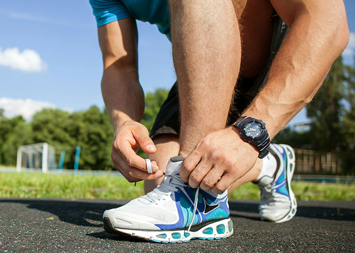 Person about to smoke a cigarette while tying running shoes, highlighting habits that reduce life quality and cause regret.
