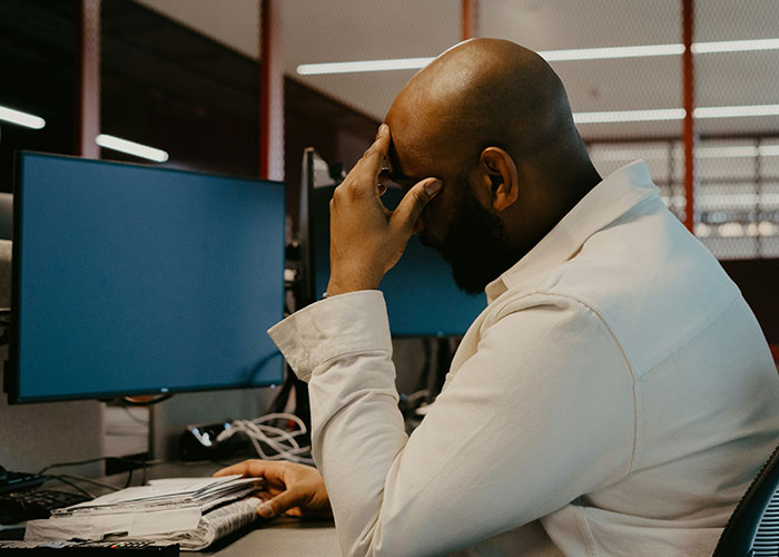Man sitting at a desk with head in hand, showing regret related to habits and decisions that reduce life quality.