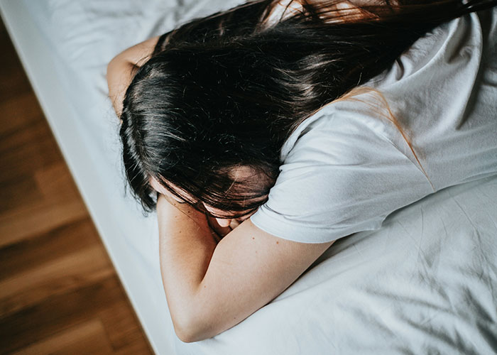 Person lying face down on a bed, illustrating habits and decisions that significantly reduced their life quality and regret.