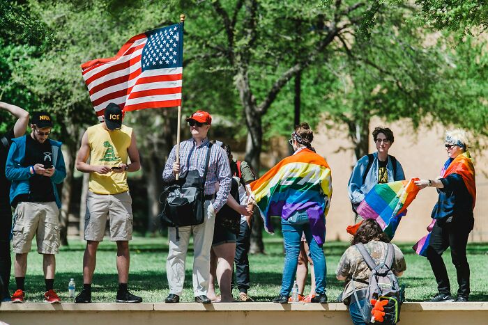 Group of travelers outdoors in colorful attire, some holding the U.S. flag, sharing surprising things about the U.S. visit.