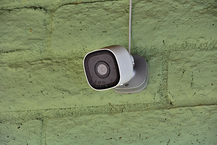 Security camera mounted on a green brick wall monitoring a house after a pregnant lady catches neighbor lurking. - 15
