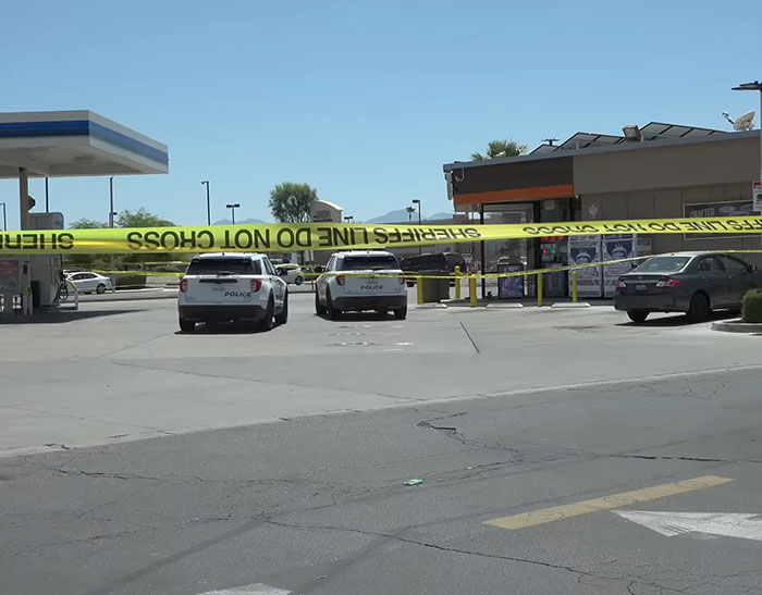 Police vehicles parked outside a convenience store with yellow crime scene tape surrounding the area after a horrifying teddy bear discovery.