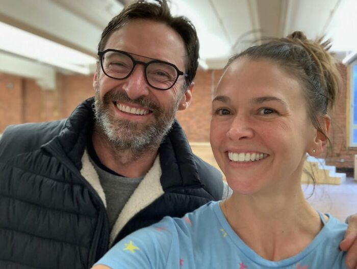 Hugh Jackman smiling with Sutton Foster indoors, highlighting their close and friendly relationship moment.