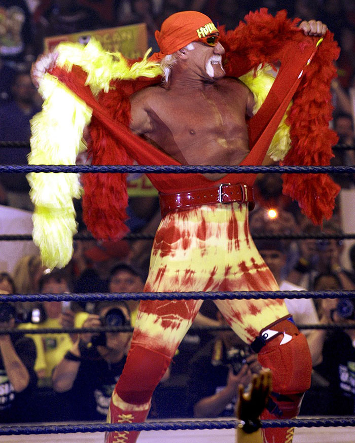 Hulk Hogan in colorful wrestling attire performing in ring during a live wrestling event with audience in background