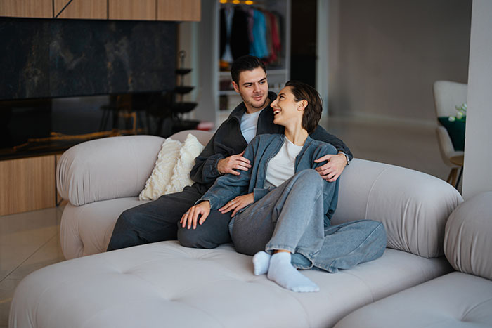 Couple sitting closely on a couch with the husband showing emotional reunion feelings, raising red flags for wife.