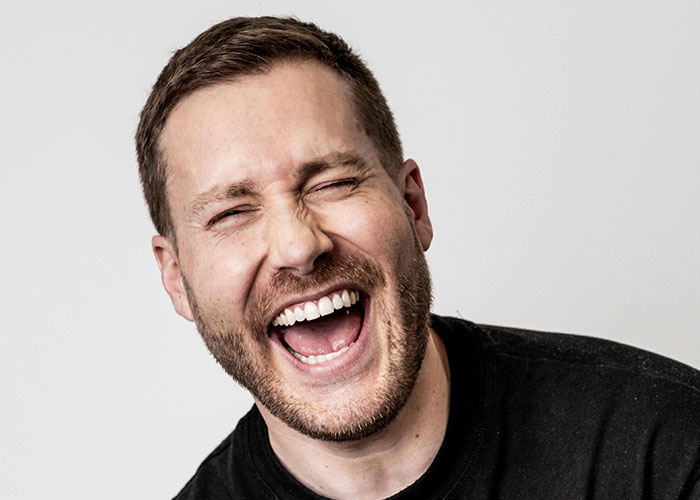 Man laughing with eyes closed wearing a black shirt, symbolizing relief after leaving manipulative husband with internet help - 12