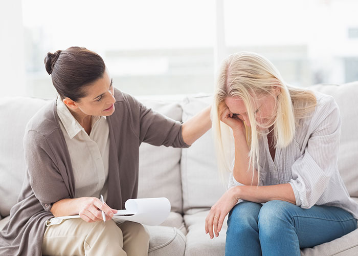 Woman comforting a distressed woman on couch symbolizing support for leaving manipulative husband with internet help. - 39
