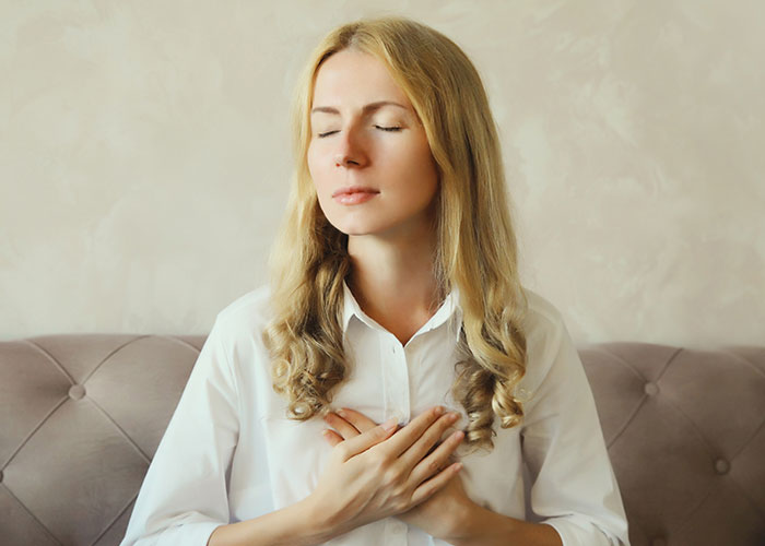 Woman with closed eyes holding her chest, reflecting on leaving manipulative husband with the help of the internet. - 72