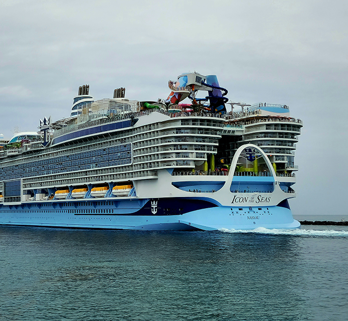 Large cruise ship Icon of the Seas sailing with passengers near the infinity pool edge of the ship on a cloudy day. - 1