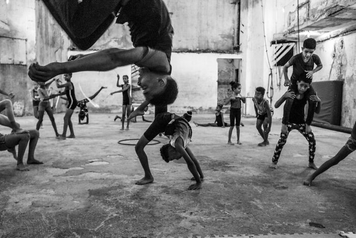 Black and white street photos capturing children practicing acrobatics and play in an old industrial urban setting.