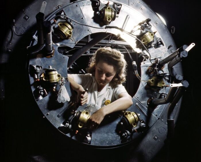 Woman working on industrial machinery, showcasing the bold and brilliant world of women at work during WWII.