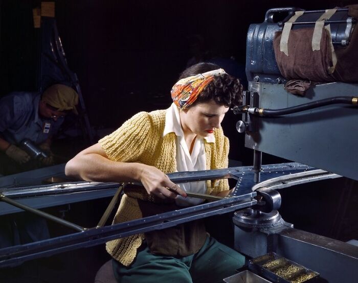 Woman worker wearing a headscarf operating machinery in a factory, representing women at work during WWII.
