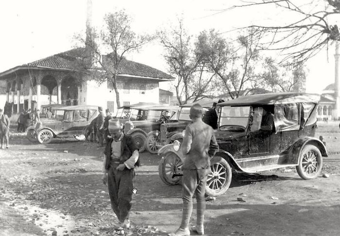 Children standing near vintage cars in a historical photograph showing what the world looked like 100 years ago.