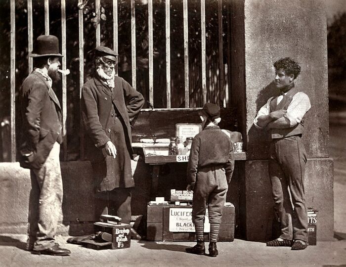 Four Victorian-era Londoners, including a boy, gathered around a street vendor’s cart showing how London's poorest really lived in the 1800s.