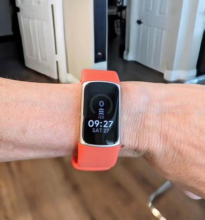 Fitness tracker with orange band worn on wrist showcasing time and step count for 20 deals on brands this Prime Day.