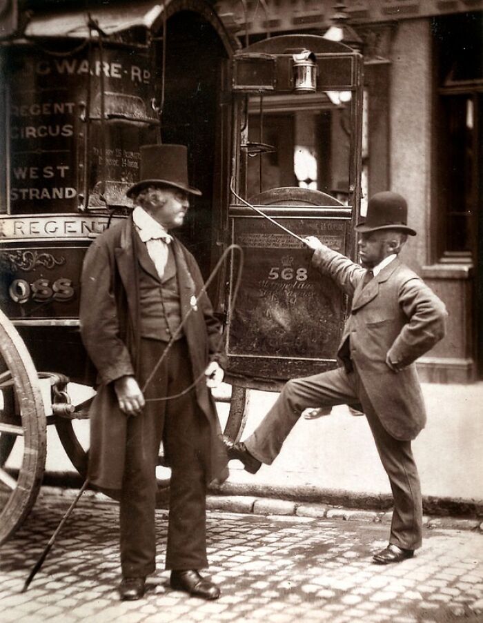 Two men in 1800s London attire standing by a horse-drawn carriage that reflects London's poorest living conditions.