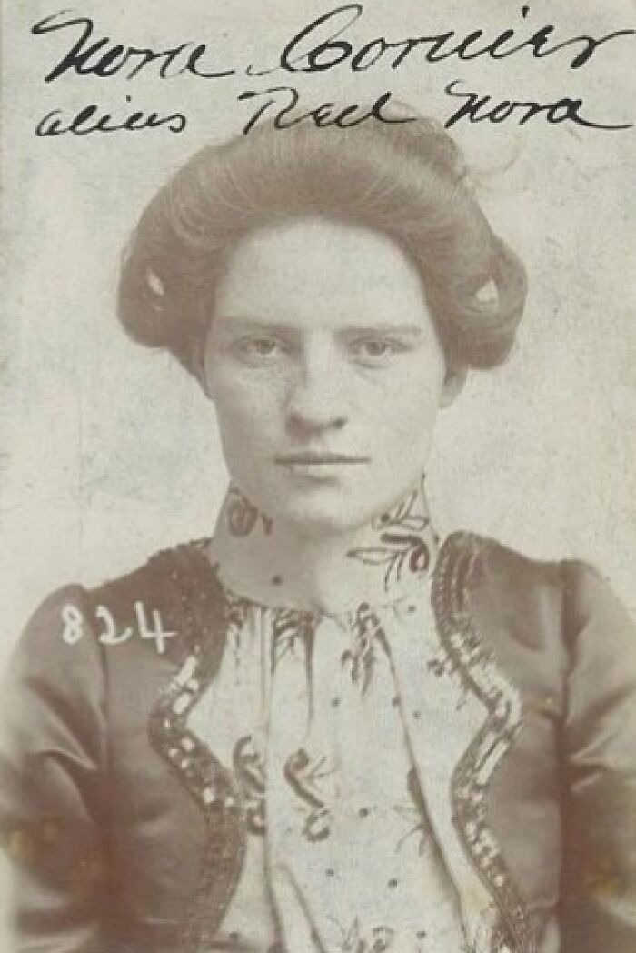 Vintage historical mugshot of a woman with braided hair and intricate patterned clothing from early 1900s collection.
