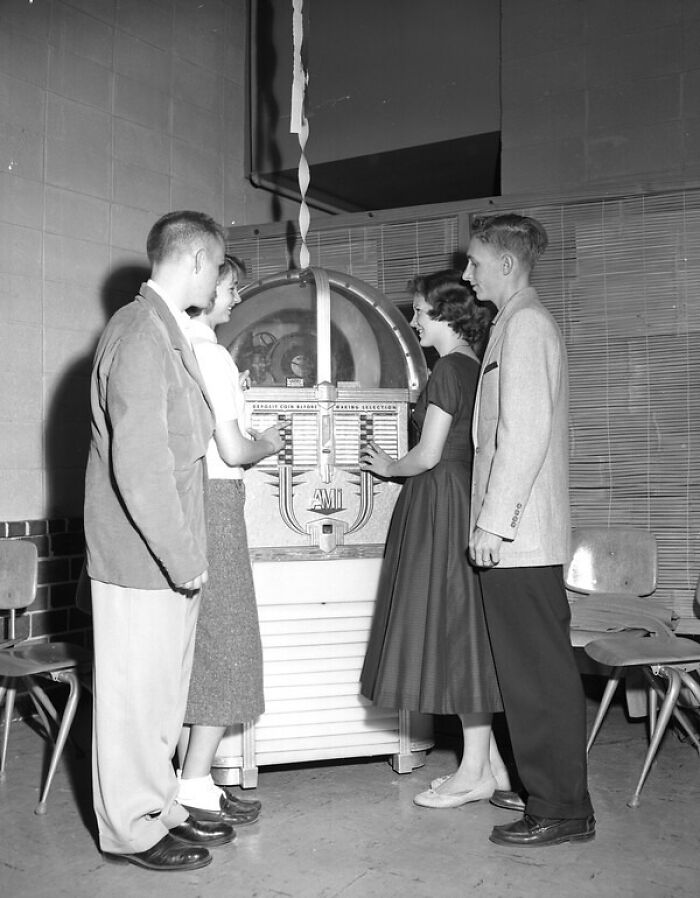 Four young people in 1950s attire enjoying a jukebox, capturing everyday life in 1950s Florida social settings.