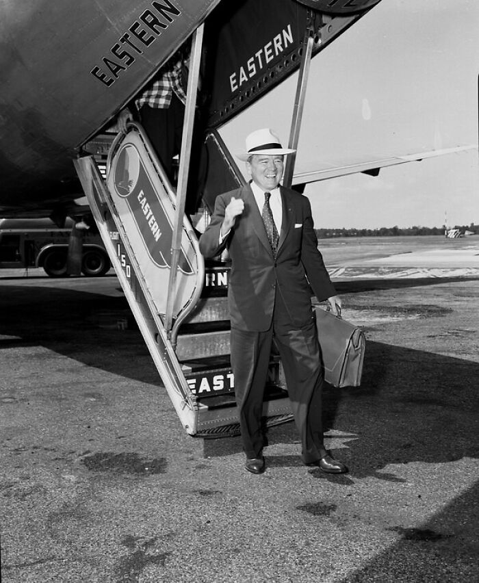 Smiling man in a suit and hat stepping off an Eastern airplane, capturing everyday life in 1950s Florida.