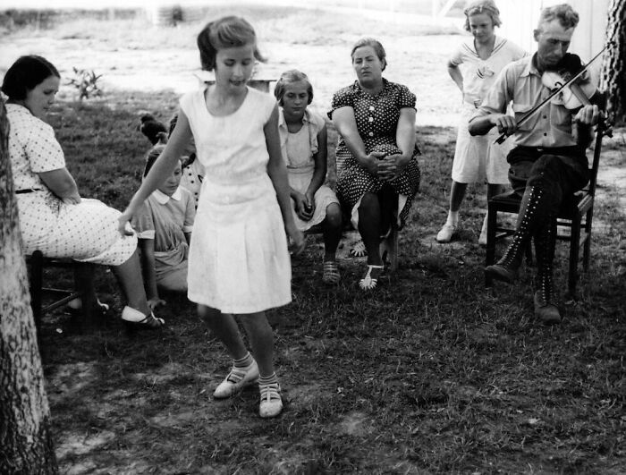 Children and adults enjoying music and dancing outdoors during the Great Depression era in a rural setting