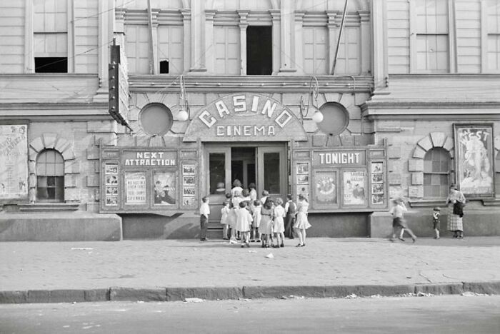 Group of children gathered outside a casino cinema building, capturing a rare photo from the Great Depression era.