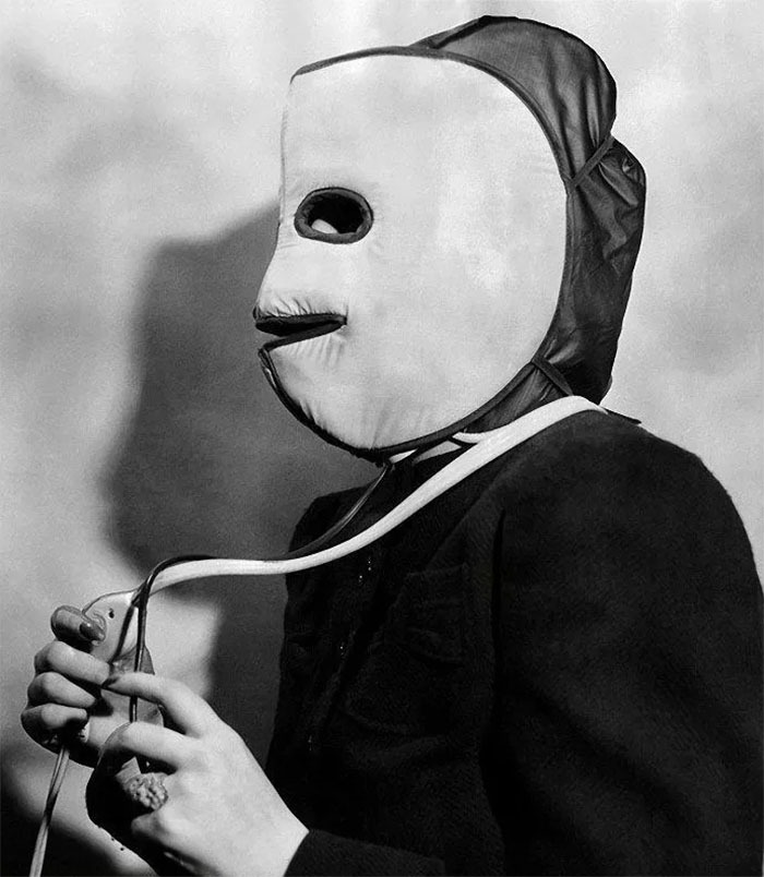 Vintage beauty gadget from the 1920s-40s resembling a mask with electrical wires held by a person in dark clothing.