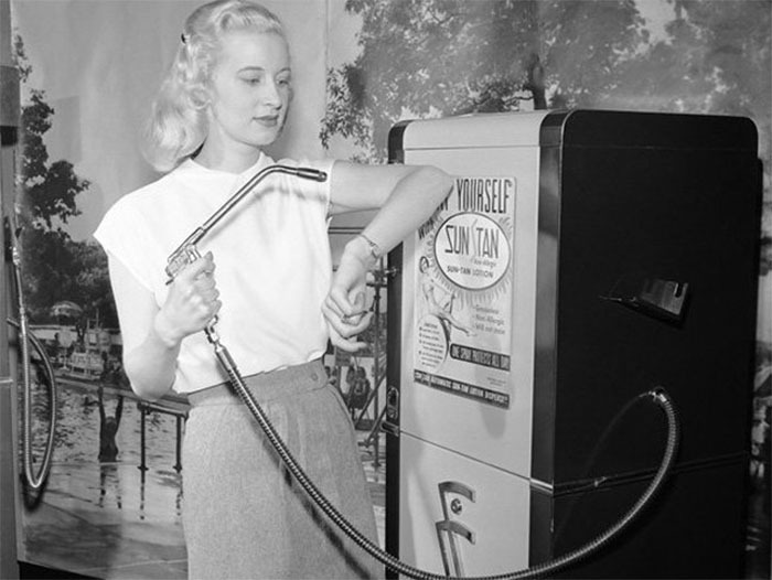 Black and white photo of a woman testing a vintage beauty gadget resembling a t*****e device from the 1920s-1940s.