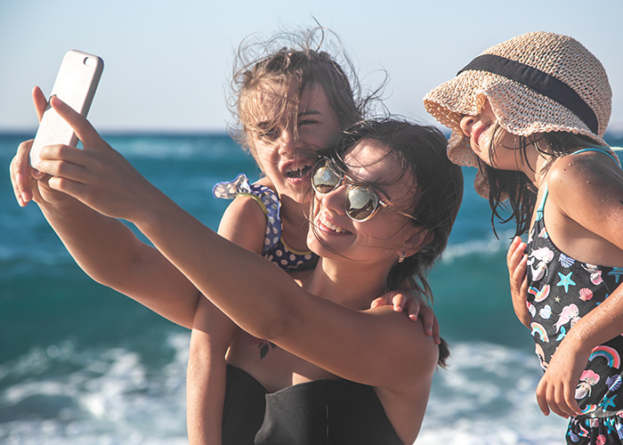Momfluencer taking a staged beach day selfie with her daughter, facing online backlash over pretend life for fame. - 2