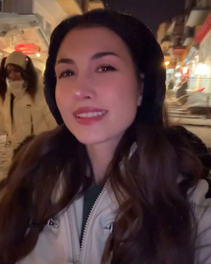 Young woman outdoors at night wearing winter clothes, illustrating influencer travel hack backfiring with shipped hotel clothes.