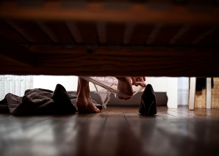 Feet of a person under a bed with shoes and clothing, creating a creepy true story scene that haunts people.