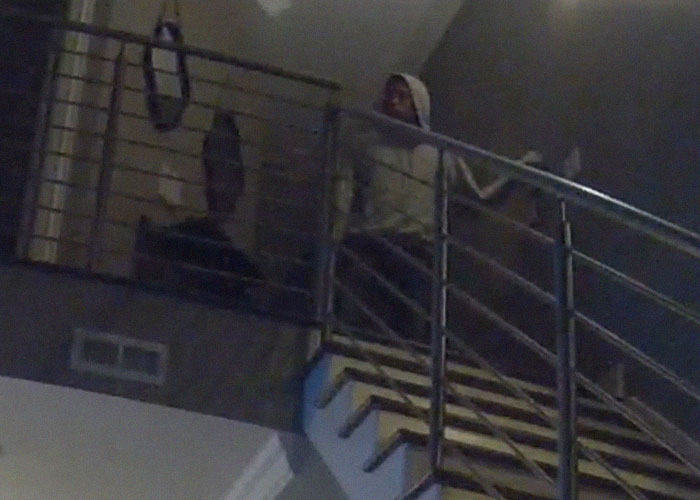 Person in a hoodie sitting on stairs in dim lighting, evoking creepy true stories that haunt people mood.