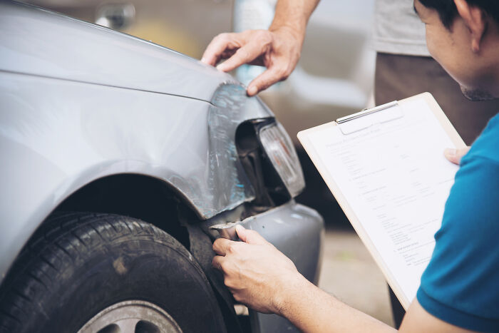 Image of two men inspecting a damaged car with a checklist, illustrating the process of scientists sharing use of bodies donated for science.