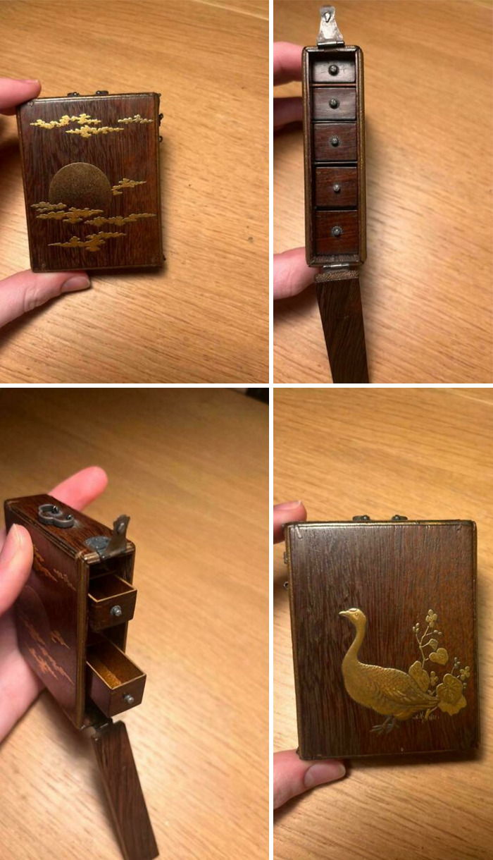 Antique wooden box with detailed gold inlay featuring a sun, clouds, and a bird, showing multiple small drawers inside.