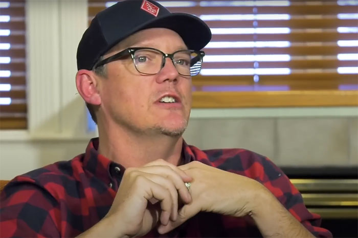 Man in glasses and a cap sharing an awkward encounter with celebrities in a casual indoor setting. - 8