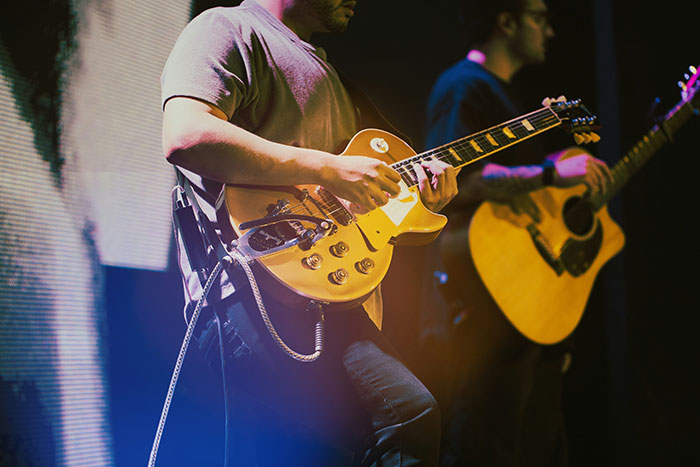 Two musicians playing electric and acoustic guitars on stage during a live celebrity encounter performance. - 12