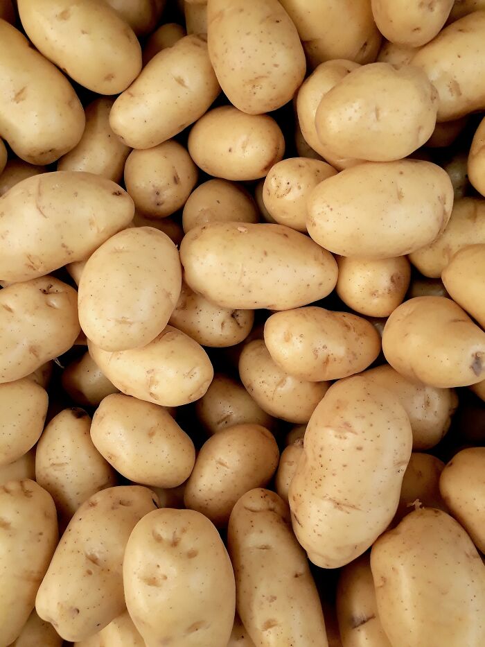 Close-up of a pile of raw potatoes with light brown skin, highlighting natural texture and slight imperfections.