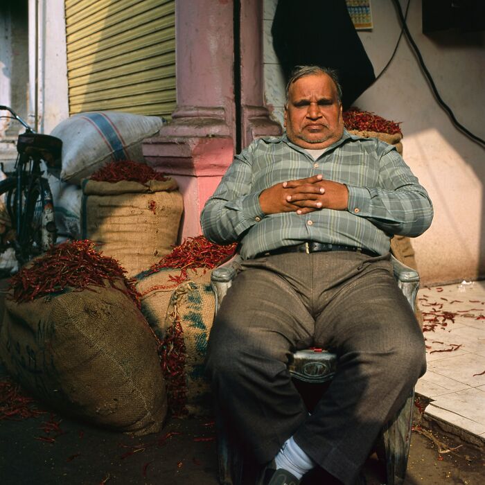 Man sitting beside sacks of dried red chilies in a market, illustrating Singapore experienced mass panic over shrinking genitals.
